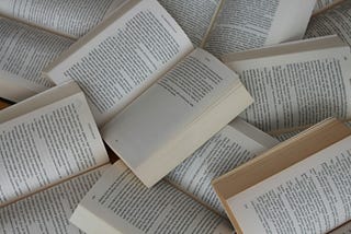 Scattered paperback books, open at different pages.