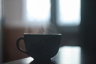 A small teacup with steam radiating from it