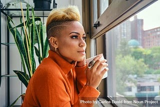Black woman thinking deeply over a cup of coffee at the window