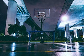 basketball hoop under a bridge at night