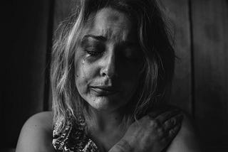 Black and white photo of a blond woman crying with tears rolling down her face.