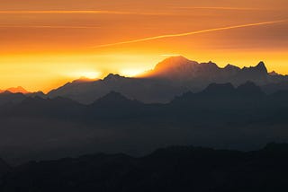 The sun glowing behind a mountain.