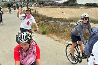 Bicyclists along the Bay Trail wearing helmets and keffiyehs smile and wave as they complete the Ride for Palestine.