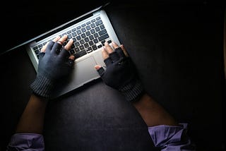 hands with gloves typing on laptop