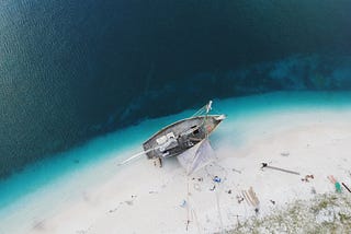 Aerial photo of a ship on a beach being worked on.
