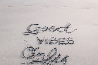 The words ‘Good Vibes Only’ drawn in the sand of a beach.