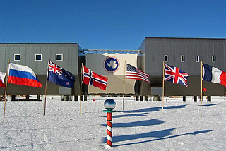 The Amundsen-Scott South Pole base, with the flags of some of the Antarctic Treaty System parties visible by the geographic south pole: Russia, New Zealand, Norway, the United States, the United Kingdom, and France.