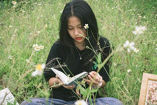 Woman sitting among daises, reading