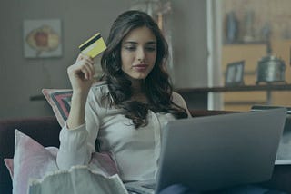 Woman with laptop holding up her credit card. Stock photo used to represent the hotel website design features you need.