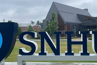 Me standing next to a large SNHU sign