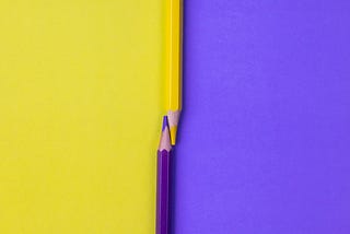 Purple and yellow crayons resting on purple and yellow background