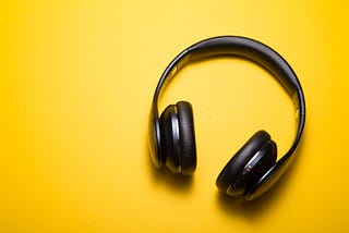 Black on-ear headphones on a warm yellow surface.