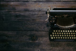 an old typewriter half shown on a wooden table