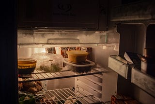 A refrigerator with food, lit only by the interior light