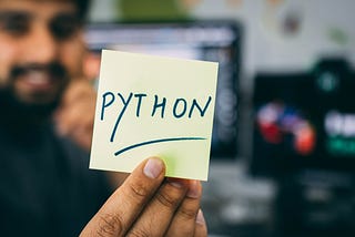 A person holding a sticky note saying Python