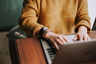 A writer sitting at a desk typing on a laptop