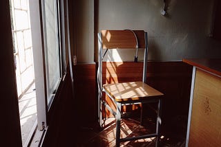 Old empty chair sits in dark classroom