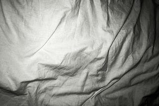White bed sheets crumpled.