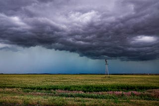 storm clouds looming over a solitary windmill in a field