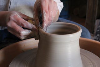 A potter shaping the top of a vase