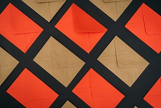 Orange and brown mails organized in a grid and laid diagonally in a checkboard fashion atop a black background.