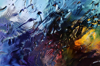 Abstract image depicting rippled surface of water, something colorful lies beneath, and shapes like birds appear to emerge from the ripples