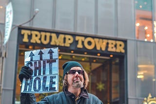 A man is holding a banner in his hand, behind he has a tower