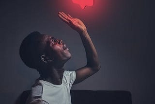 Man sitting at desk with hand in the air aiming to high five a social media icon with zero heart rating