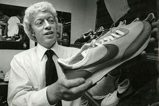 A black-and-white picture of Phil Knight, Nike’s co-founder, holding a Nike shoe.