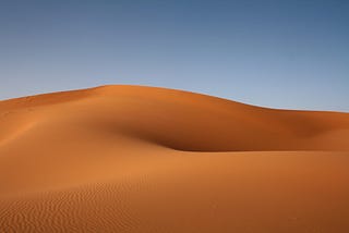 Desert sand to the horizon of blue sky