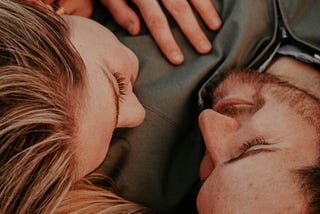 Close up of a man with a short-cropped beard and woman with blonde hair cuddling