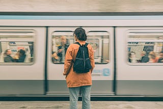 Person with backpack in front of moving train