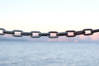 close-up of a heavy chain, with a body of water in the background