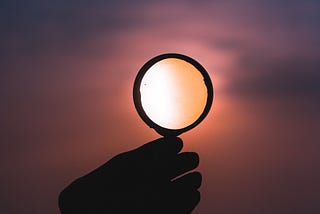 Holding a magnifying glass up to the sky.