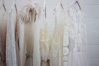 White dresses on white hangers against a white background.