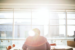 man sitting in front of sunny window in office