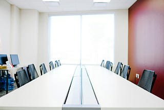 A conference table with 12 chairs, clean surface, simple.