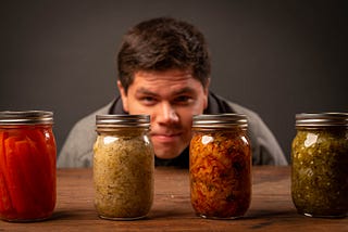 A man staring a four jars of pickles