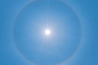 A completely clear, blue sky with the sun shining intensely in the middle of the frame.