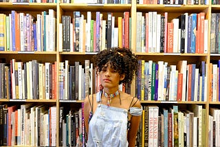 A student looks frustrated by having to find textbooks in a bookstore.