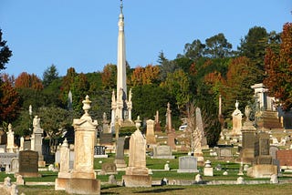 Picture of large cemetery headstones with fall color background