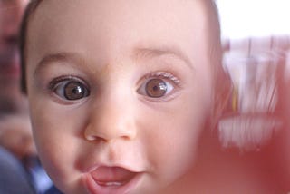 a baby’s face up close, wide eyes and open mouth, Mary Mahoney, Medium