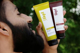 A cheerful man proudly holding hid facewash, glowing with satisfaction.