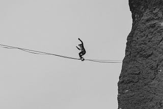 A tightrope walker focuses on keeping his balance as he makes his way across a void