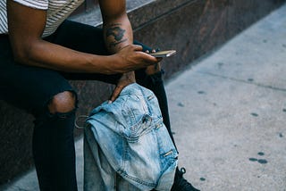 A man sitting outside a shop reading messages on his new phone