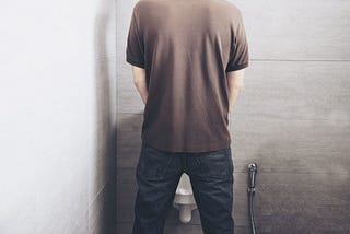 Image of a man urinating facing the lavatory.
