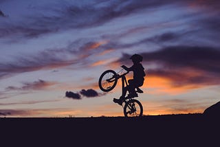 Picture of kid with bike riding on one wheel