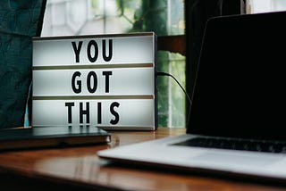 Computer Monitor next to a sign that reads “You Got This”