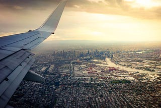 View out an airplane window overlooking a city.