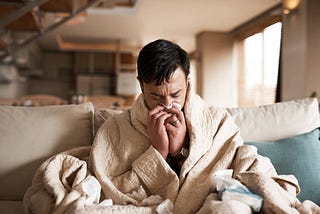 Man wrapped in blanket due to having common coldE.g.